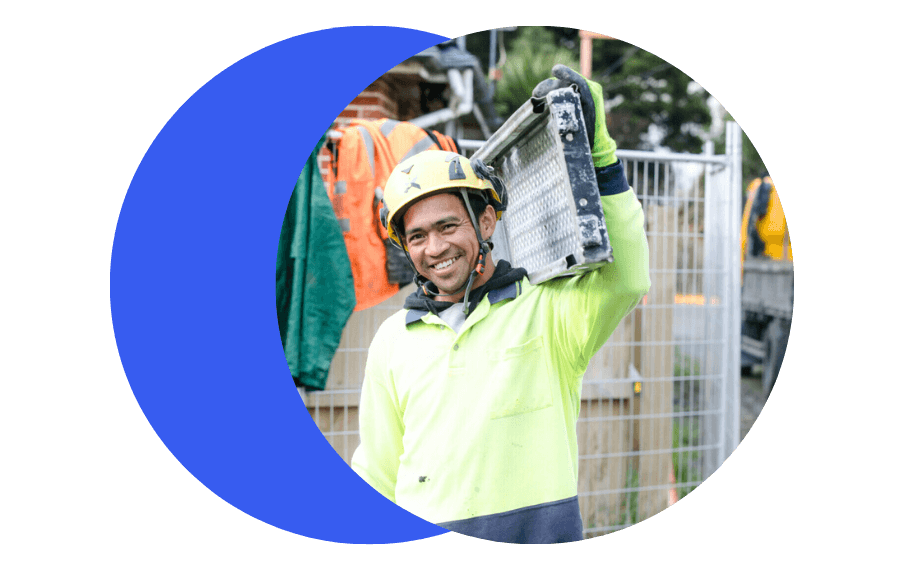 Construction worker in high vis smiling carrying a tool
